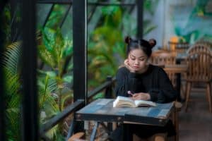 serious young asian lady reading book in cafeteria