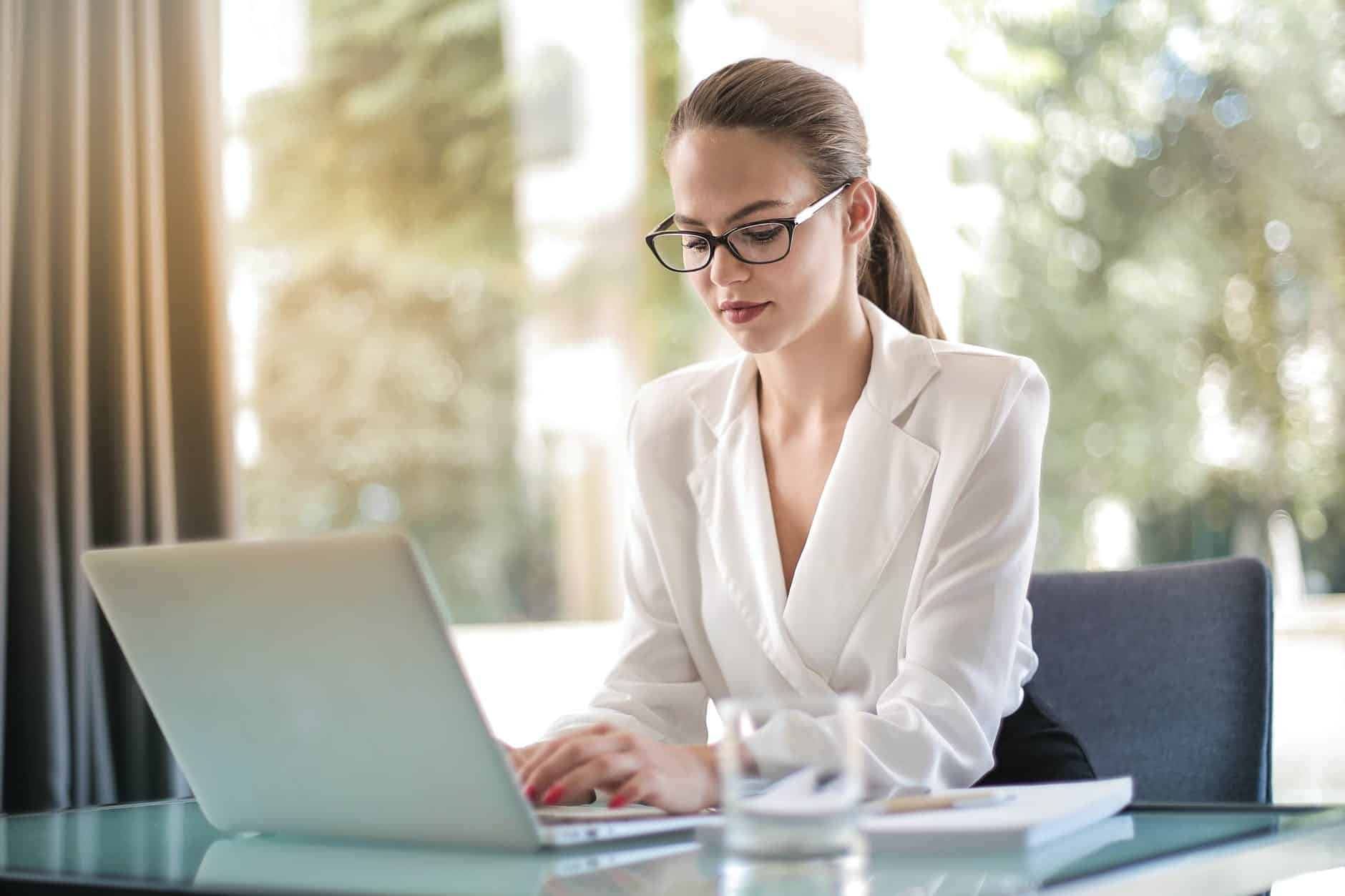 concentrated female entrepreneur typing on laptop in workplace